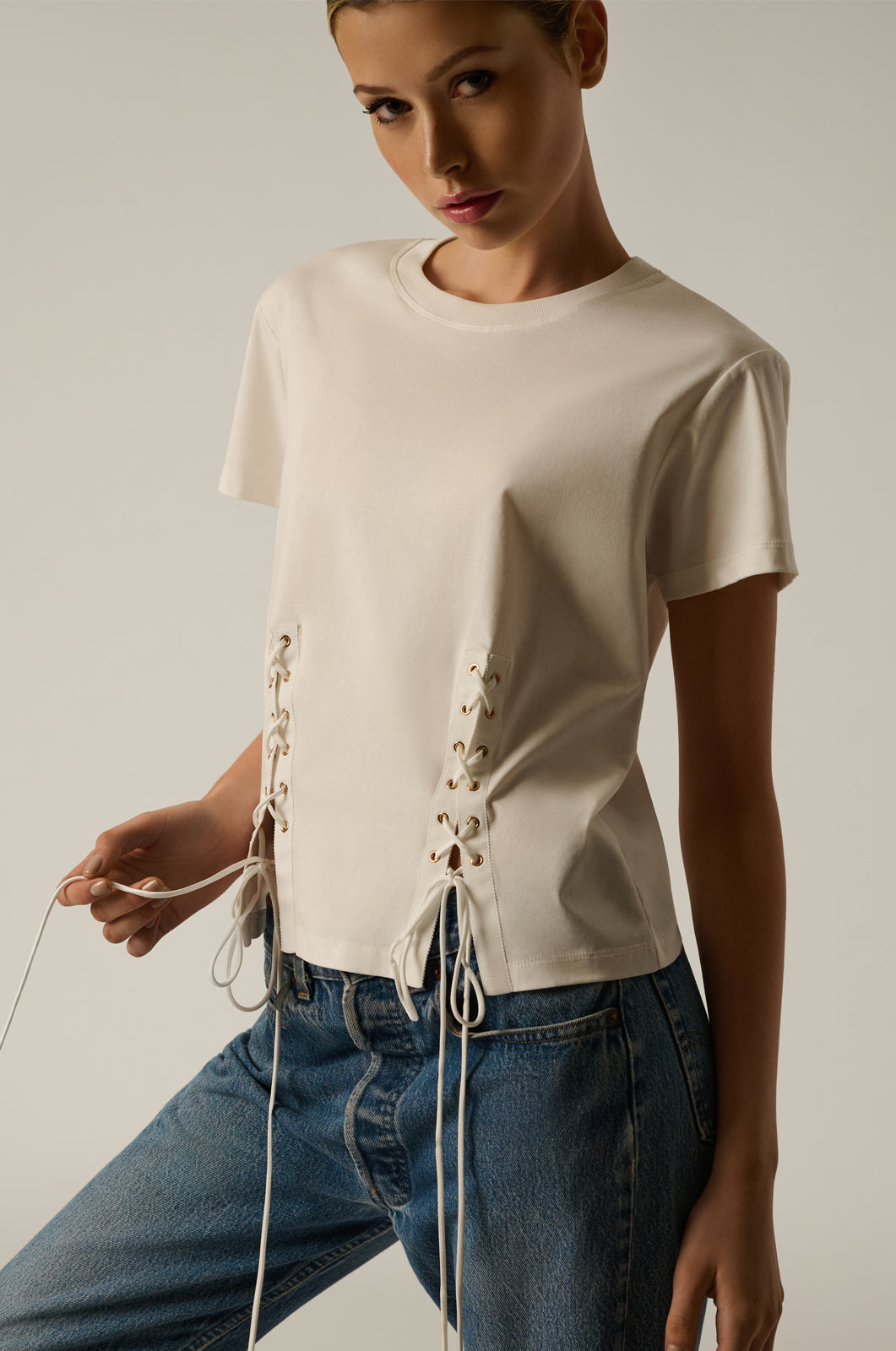 White cotton t-shirt with lace up details on front and back gold hardware front view