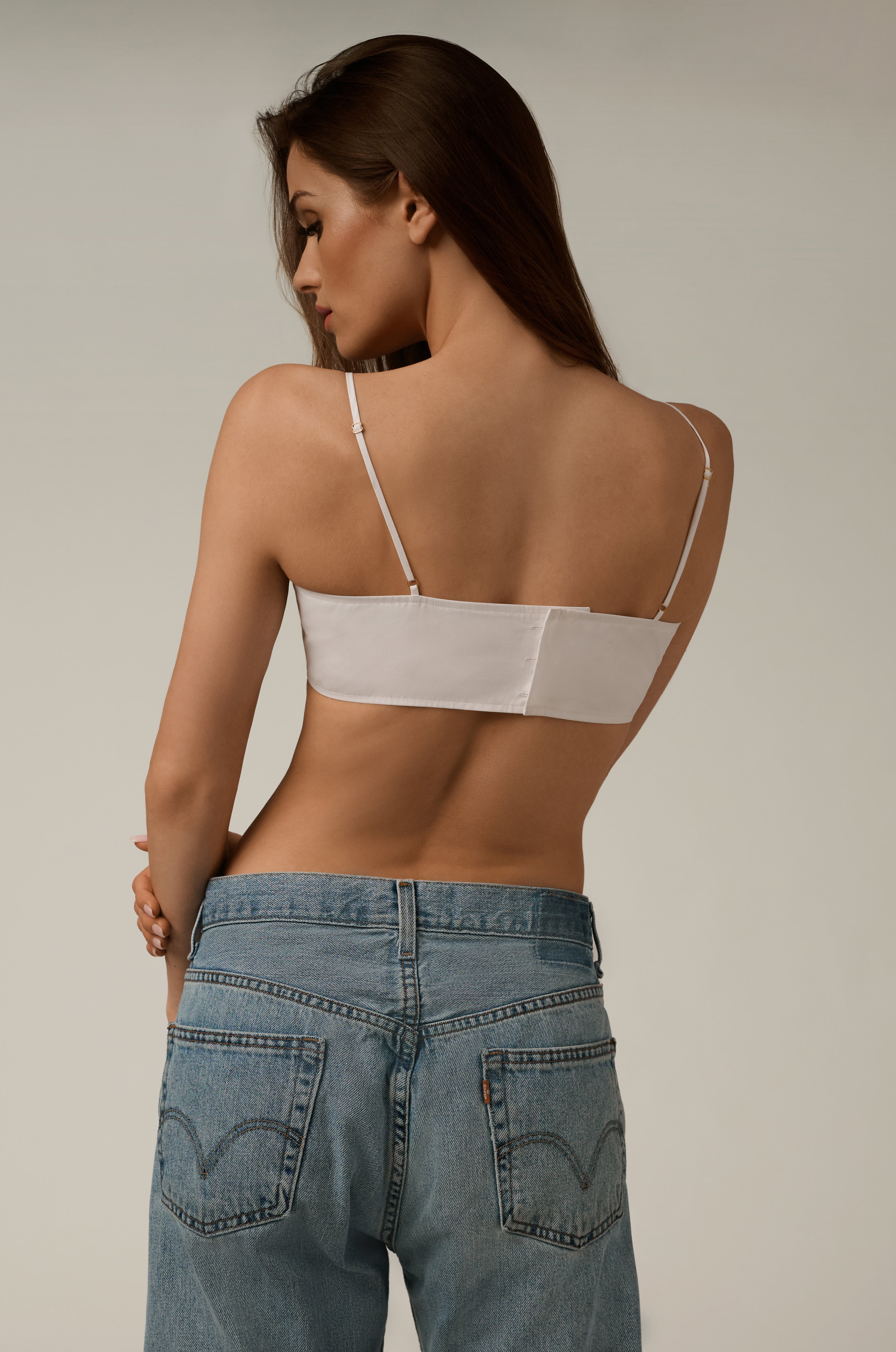 back view of white poplin bandeau top, model wearing jeans 